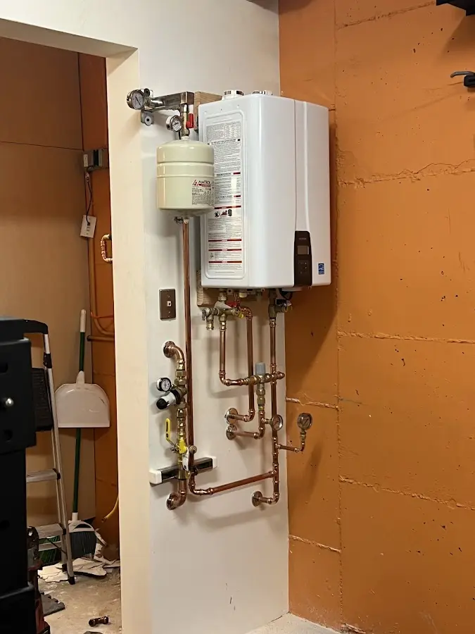 Plumbing technician inspecting water heater connections in Orchard City